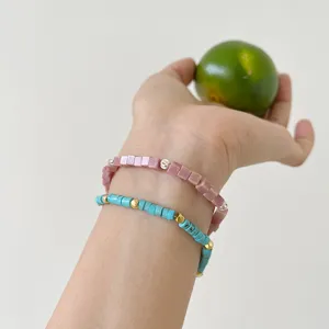 Detailed shot of double-layer beaded bracelets with pink and blue stones on the wrist.