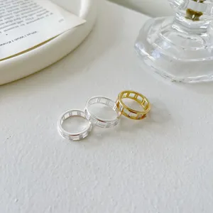 Nahaufnahme von geometrischen quadratischen Strass-Ringen in Silber und Gold.