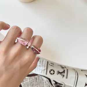 Primo piano dettagliato di anelli aperti in argento S925 con design unici di pietre rosa e rosse.