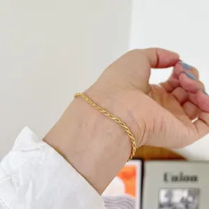 Nahaufnahme eines filigranen, vergoldeten Kordelkett-Armbands am Handgelenk, eleganter Stil.