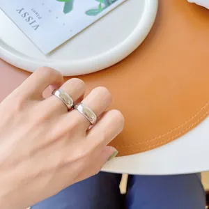 Nahaufnahme von minimalistischen, glatten silbernen Ringen an der Hand, stilvolles Schmuckdetail.