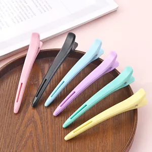 Close-up detail of colorful duckbill hair clips arranged neatly on a wooden tray for styling.