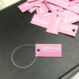 Close-up detail shot of pink square paper hang tags with strings for retail hair accessories.