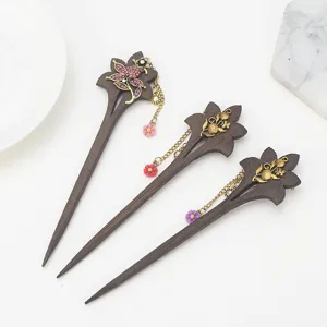 Handmade wooden hair stick with floral metal tassel, elegant vintage bun accessory detail.