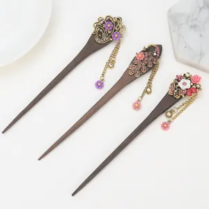 Detailed close-up of handmade wooden hair sticks with floral rhinestones and dangling tassels.