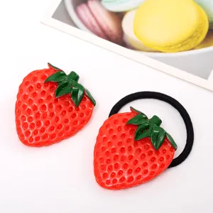 Detail view of a cute strawberry hair clip and hair tie set, featuring vibrant red fruit design.