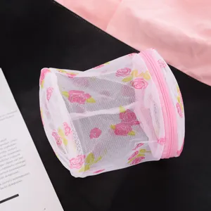 Close-up detail of the cylindrical mesh laundry bag with pink floral pattern and zipper.