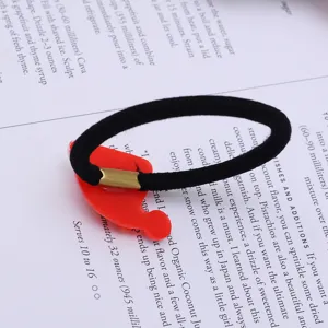 Black hair tie with red watermelon fruit pendant detail close-up, cute hair accessory.