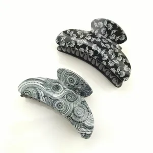 Gros plan détaillé de grandes pinces à cheveux noires et blanches aux motifs uniques.