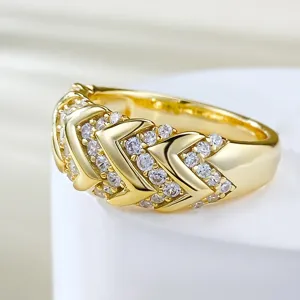 Detallado primer plano del anillo chevron de plata chapada en oro con circonitas brillantes.