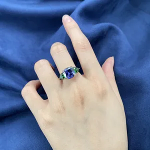 Primo piano dettagliato di un anello in tanzanite taglio cuscino con gemme verdi laterali.