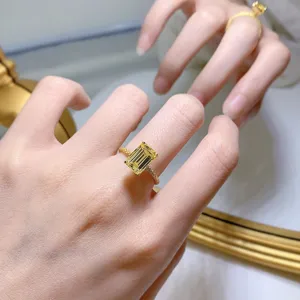 Nahaufnahme des strahlenden gelben rechteckigen Edelsteinrings, elegant am Finger getragen.