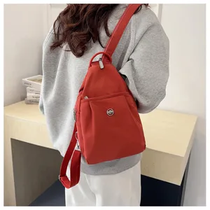 Detailansicht des roten Nylon Sling-Rucksacks mit strapazierfähigem Stoff und Fronttasche.