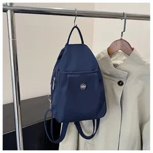 Detailansicht eines dunkelblauen Nylon-Mini-Rucksacks mit Fronttasche am Kleiderständer.