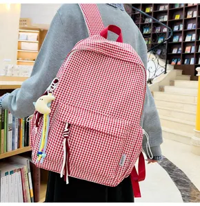 Detailansicht des rot-weißen karierten Rucksacks mit Stoffstruktur und Anhänger.