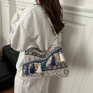 Vista detallada del bolso de hombro tejido bohemio con patrones étnicos y borlas en el modelo.
