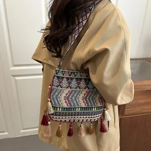 Borsa a tracolla intrecciata in stile etnico bohémien con nappe colorate e ampia tracolla.