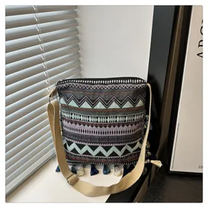 Sac bandoulière en toile géométrique style ethnique avec franges et large sangle pour le travail.