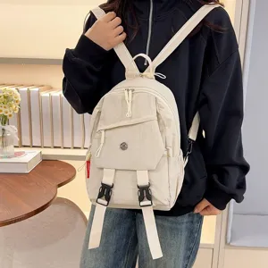 Detailopname van een beige casual rugzak gedragen door een model met twee gespen.