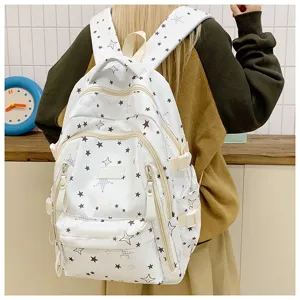 White canvas backpack detail with black star print, multiple zippered pockets and straps.