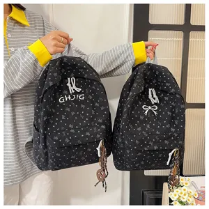 Close-up view of casual canvas backpack featuring cute bow and heart prints with embroidery details.