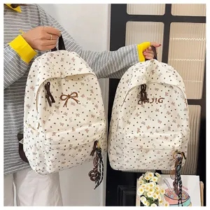 Close-up detail of casual canvas backpacks featuring cute bow prints and letter embroidery.