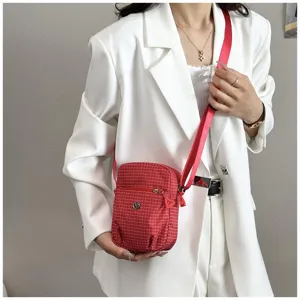 Red plaid nylon crossbody bag for women, small vertical shoulder bag with front zipper pocket.
