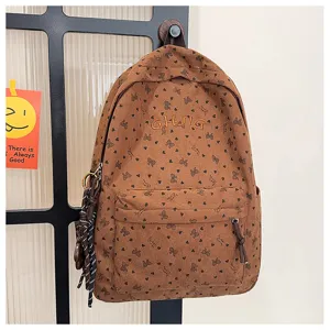 Brown corduroy backpack with bow print and front pocket, perfect for casual travel and daily use.