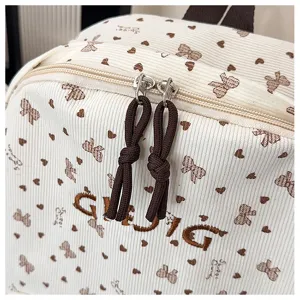 Cute corduroy backpack detail featuring bow heart print and embroidery, zipper closure.