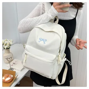 Detailed view of sweet Japanese style white school backpack featuring cute blue bow embroidery.