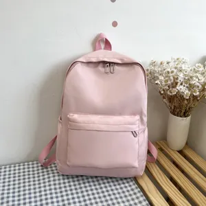 Dettaglio zaino rosa con tasca frontale con zip e texture in tessuto liscio in scena.