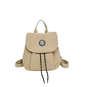 Beau sac a dos de voyage pour femme en tissu beige avec cordon de serrage et poignee.