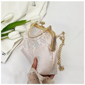 Detailed view of a Chinese style pink brocade kiss lock handbag with elegant gold metal handle.