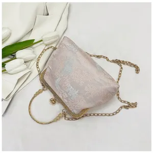 Detailed view of a Chinese style vintage brocade clutch bag with metal handle and chain strap.