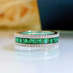 Detalle en primer plano del precioso anillo de piedra preciosa verde con borde de diamantes.