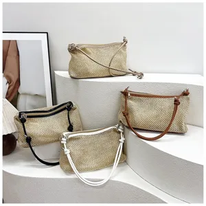 Detailed view of fashionable woven straw shoulder bags with contrast straps for summer beach use.