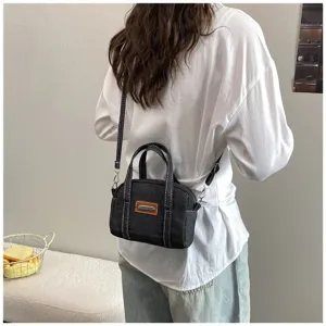 Detailansicht der stilvollen dunklen Denim Umhängetasche mit weißen Kontrastnähten.