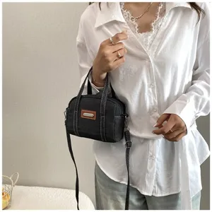 Nahaufnahme Detail der Vintage Jeans Mini Handtasche mit Kontrastnähten und Metallpatch.