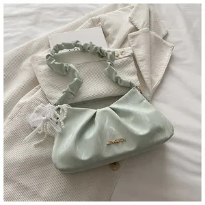 Detail shot of light green ruched cloud underarm bag with elegant pearl lace pendant.