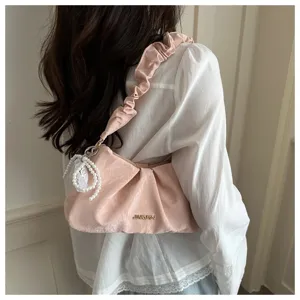 Detailed view of pink pleated underarm bag with pearl pendant, elegant design for women.