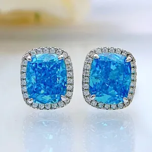 Nahaufnahme von kissengeschliffenen blauen Ohrringen mit funkelndem Halo Detail, Makrofotografie.