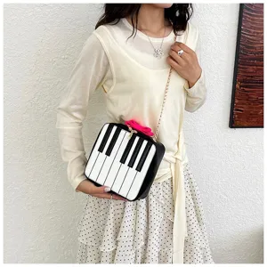 Creative piano keys crossbody bag featuring a gold chain strap and cute pink bow.