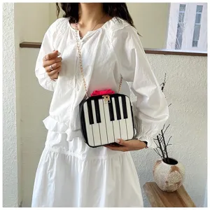 Detailed view of cute piano keys design mini crossbody bag featuring chain and pink bow accent.