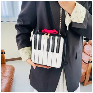 Detailed view of a creative piano keyboard crossbody bag featuring cute pink bow and chain.