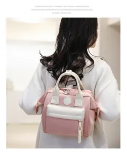 Stylish pink mommy backpack with white top handles and front pocket, perfect for daily travel.