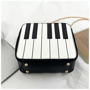 Mini piano keys design crossbody shoulder bag with gold chain strap and metal feet details.