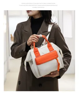 Detail view of the white and orange canvas tote handbag with front pocket and braided charm.