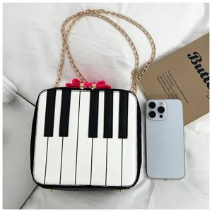 Detailed shot of creative piano keys crossbody bag with gold chain and cute pink bow.