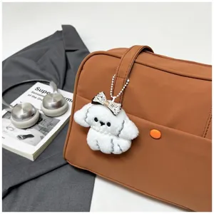 Close-up detail view of the casual brown shoulder bag showing soft texture and plush dog pendant.