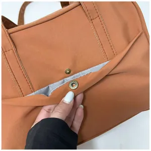 Detail view of casual nylon tote bag showing front snap button pocket and neat stitching.